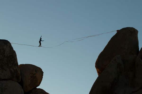 a persion walking a tightrope between two rocks and not being moved by what they see
