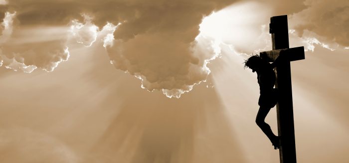 Jesus hanging on a cross with a golden sky background showing why humanity needs redemption