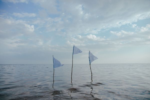 three white flags protruding from the ocean illustrating living a surrendered life to god