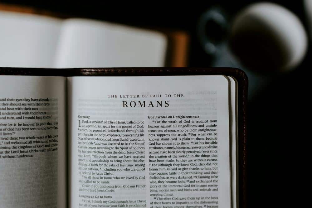 a bible opened to the book of romans which describes the work of biblical redemption