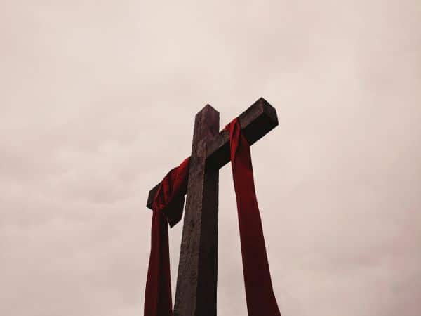 a wooden cross with a red garment hanging off of it illustrating biblical redemption through the cross