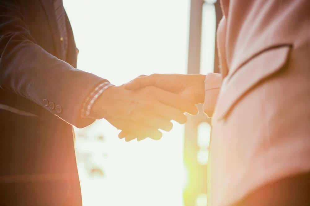 two people shaking hands illustrating that atheism and evolution go hand in hand