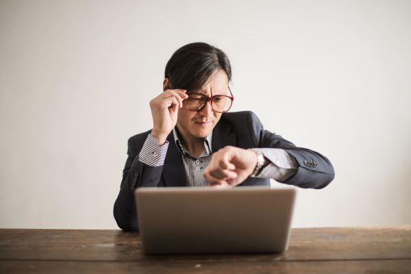 getting ahead of god devotional cover image with a man looking at his watch in impatience sitting in front of his laptop