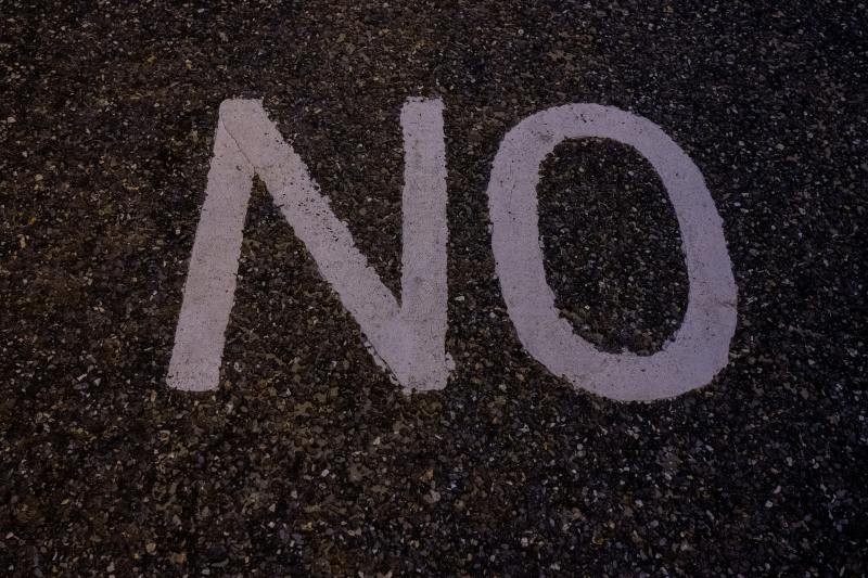 white paint on a black surface that spells out "no"